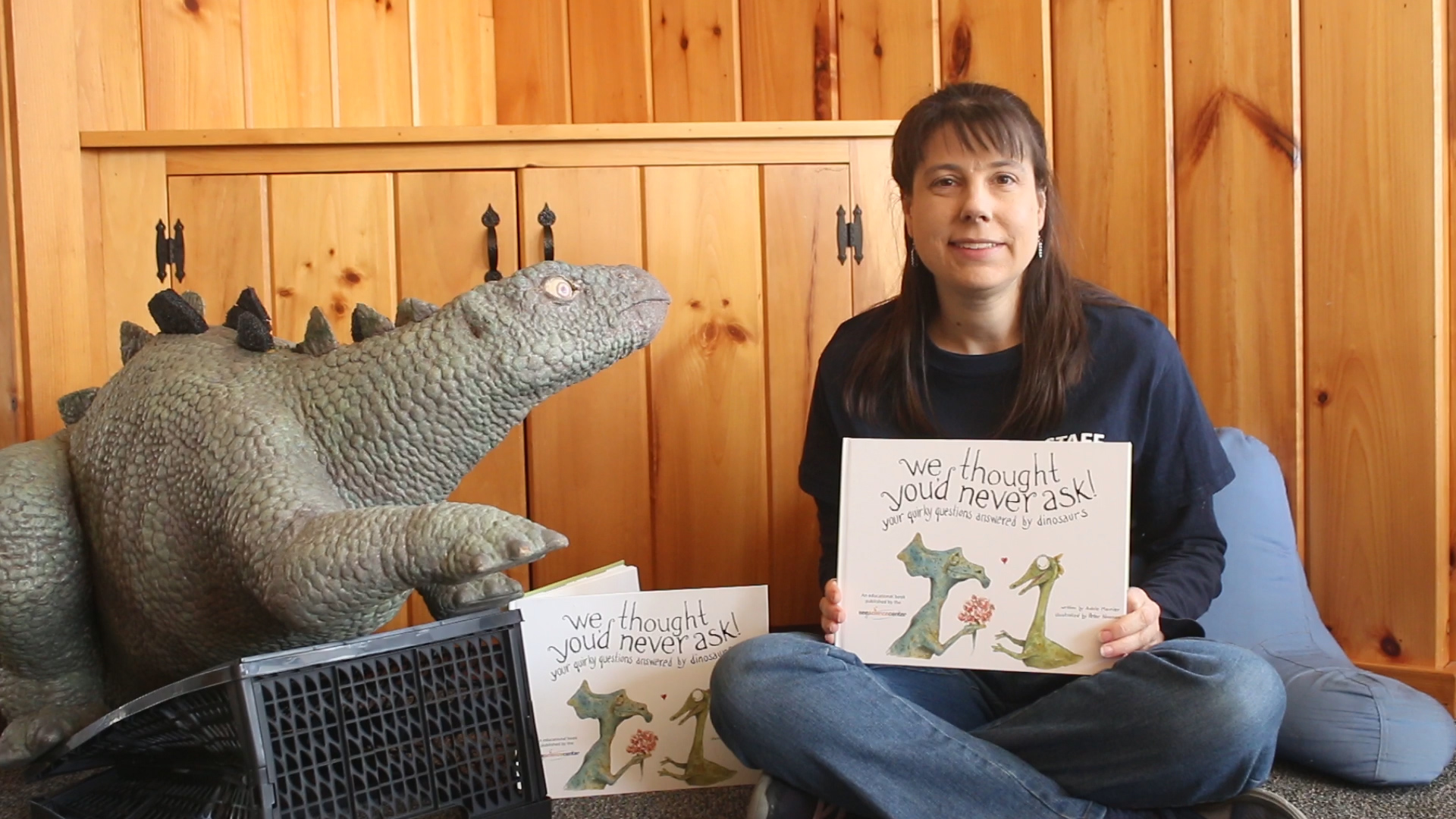 woman seated with stuffed dinosaur and book