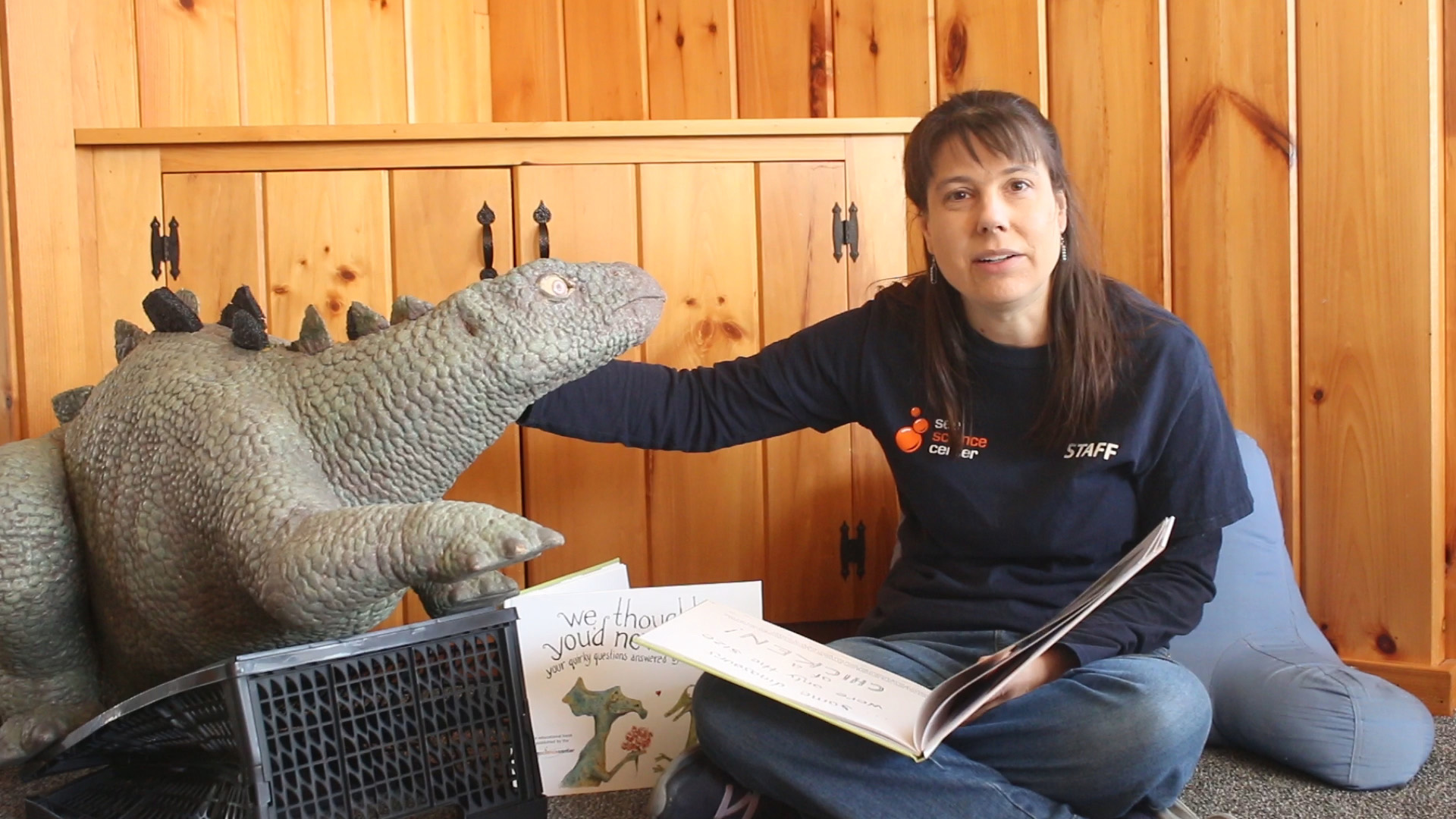 Woman with book with dinosaur model