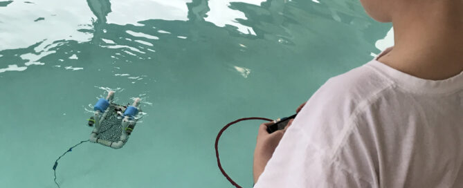 a camper operates an underwater robot in a pool.