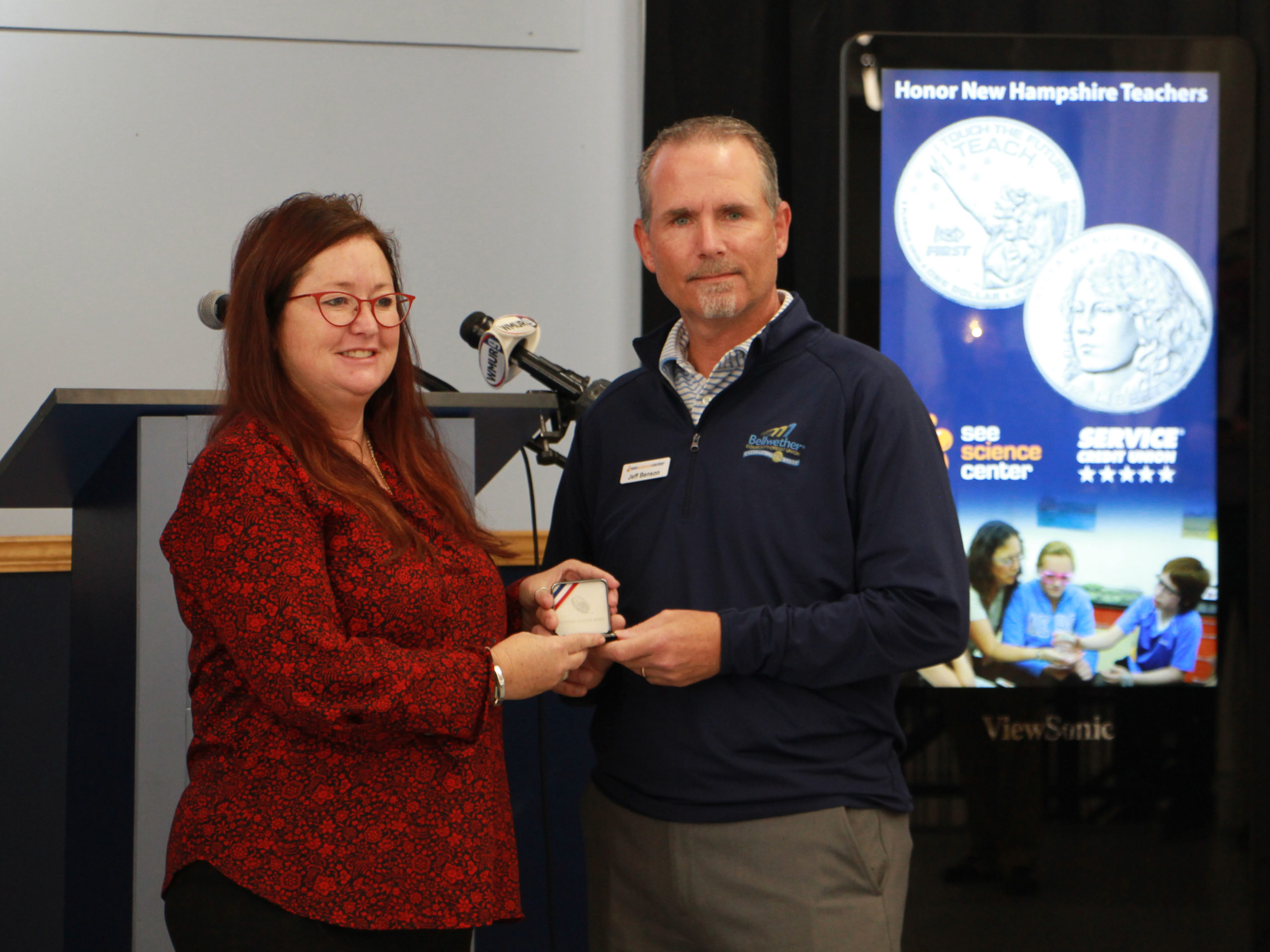 Assistant Manchester School District Superindendant Amy Allen receives coins for Manchester teachers from SEE board chair Jeff Benson
