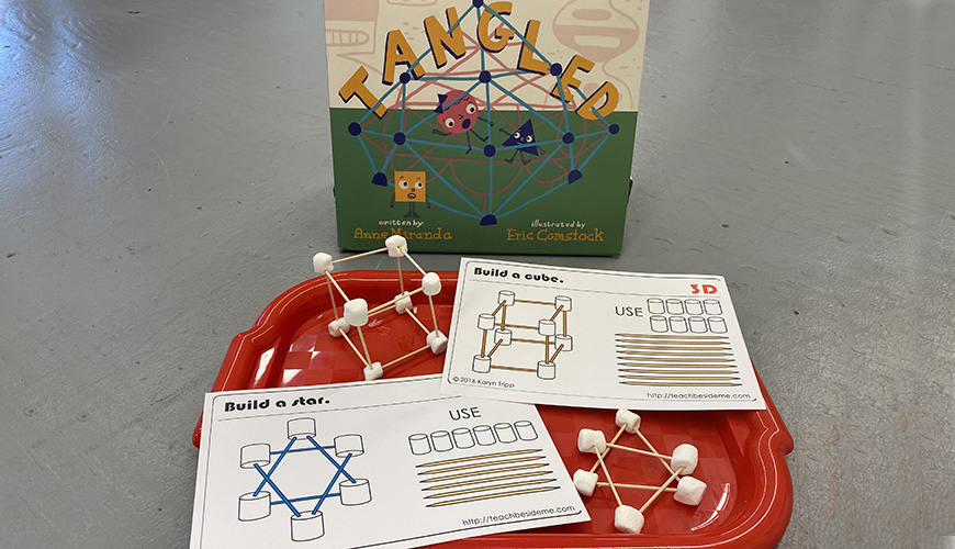 A book and a tray with shapes made of spagetti and marshmallows