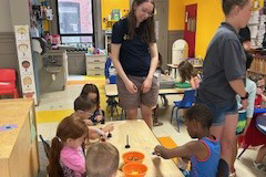 an educator helps young children with a storytime science actvity.