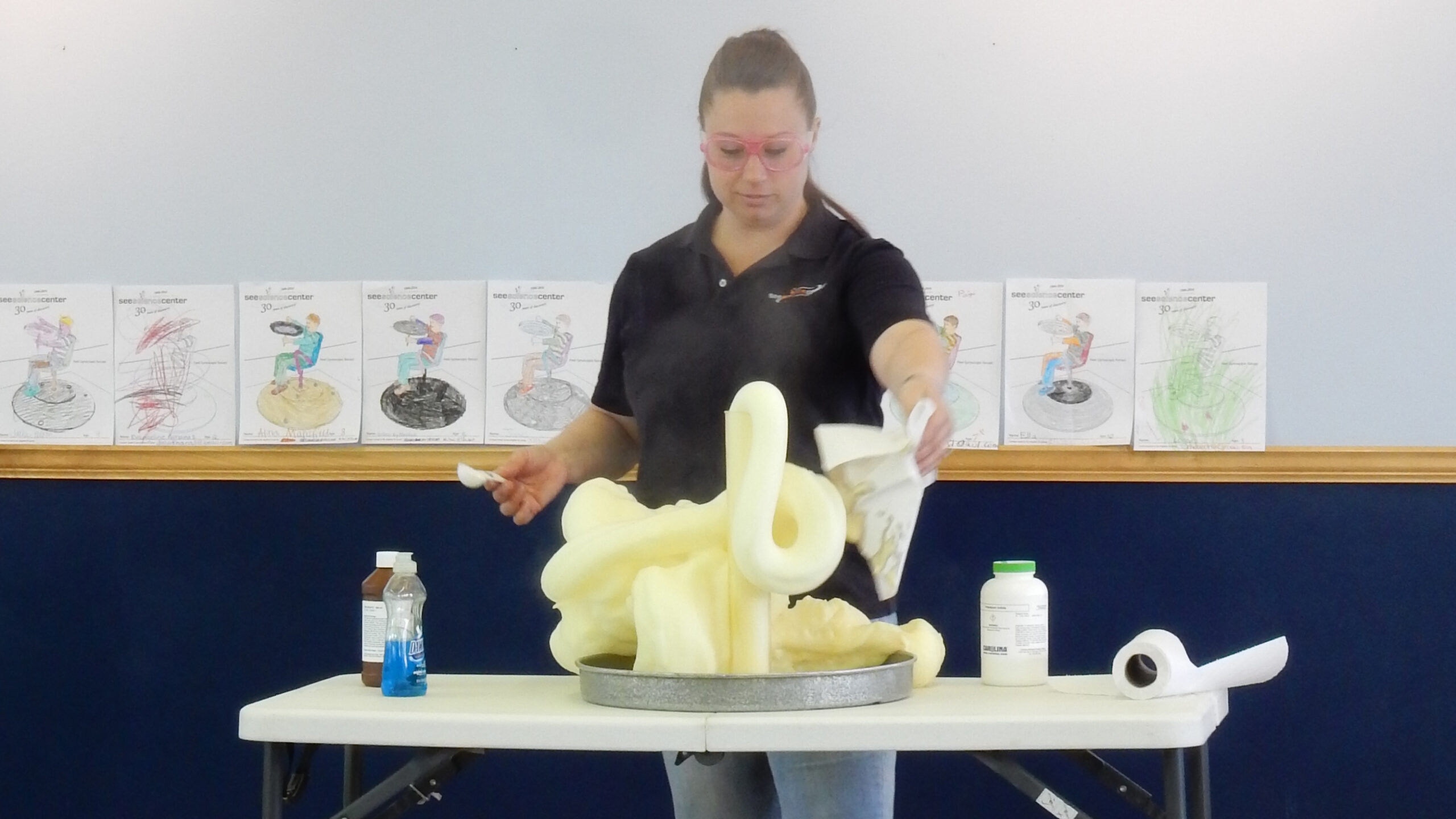 A see educator stands behind a chemical reaction called elephant's toothpaste.
