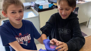 Two students hold do an experiment in their classroom.