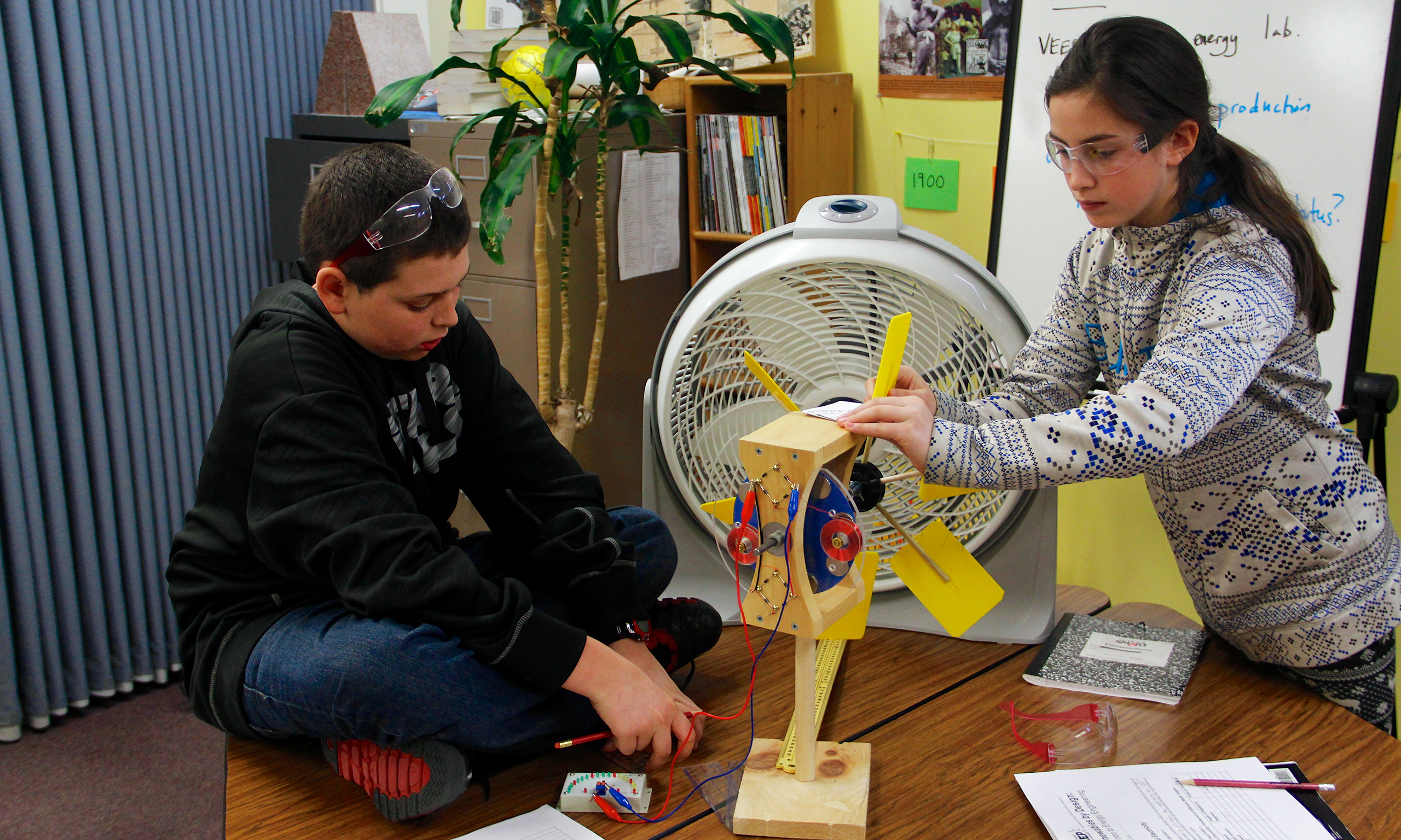 a boy and a girl work with a fan an turbine blade