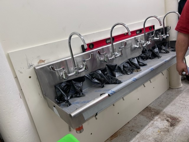 A sink with four faucets is shown on the wall in the lab.