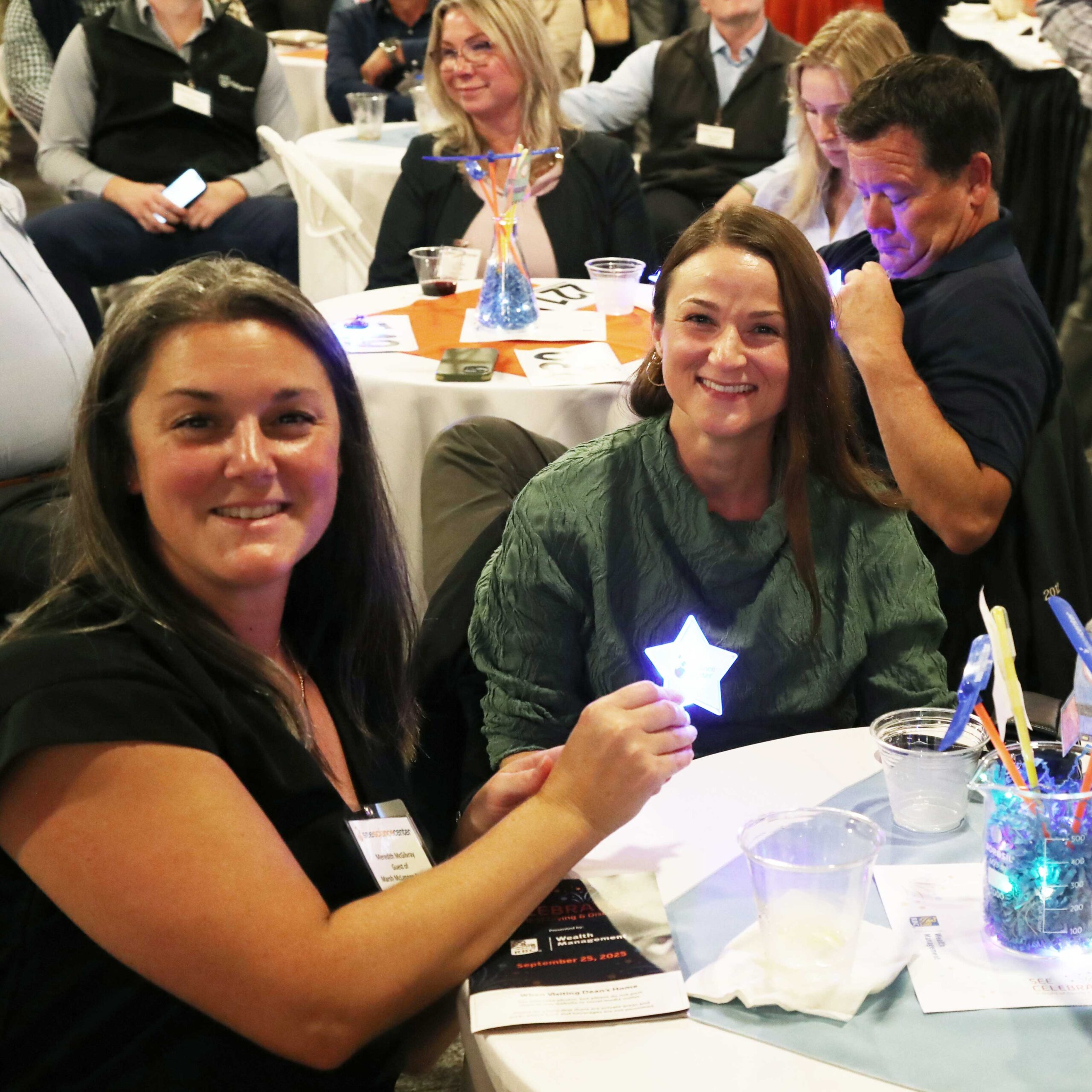donors hold up their stars at their table