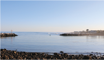 Image of the ocean shore in New Hampshire looking out at the gulf of Maine with calm seas.
